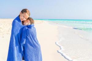 adorables niñas envueltas en toallas en una playa tropical después de nadar en el mar foto