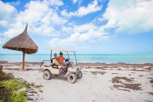 Little girl with father golf cart on tropical beach photo