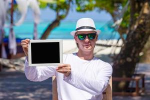 joven en la playa con tablet PC. mostrando pantalla pc digital foto