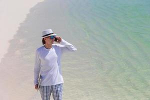 Young business man calling by cell phone on white beach photo