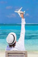 Joven con miniatura de un avión en playa tropical foto