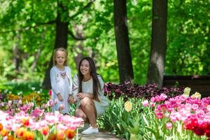 adorable niña y madre joven disfrutando de un día cálido en el jardín de tulipanes foto