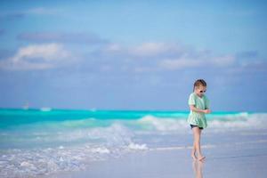 Adorable little girl walking along white sand caribbean beach photo