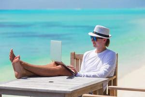 Young man with tablet computer on tropical beach photo