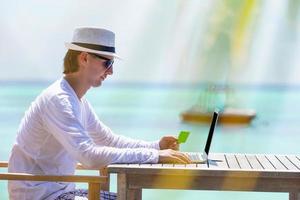 Young man with tablet computer on tropical beach photo