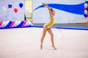 Beautiful little gymnast girl on the carpet on the competition photo