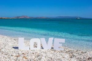 palabra amor en el fondo de la playa tropical del mar turquesa y el cielo azul foto