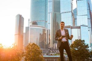 Businessman looking on copy space while standing against glass skyscraper photo