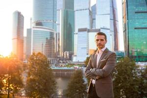 Businessman looking on copy space while standing against glass skyscraper photo