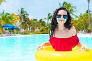 Beautiful young woman relaxing in swimming pool. Back view of girl in outdoor pool at luxury hotel photo