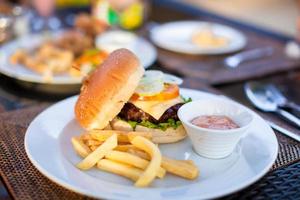 Classic burger with French fries on table in outdoor cafe photo