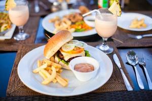 Classic burger with French fries on table in outdoor cafe photo