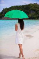 Young girl with umbrella on white beach photo