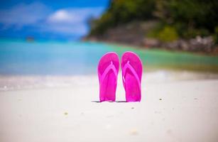 par de chancletas coloridas en la playa del mar foto