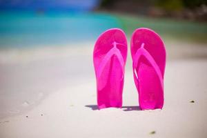 par de chancletas coloridas en la playa del mar foto