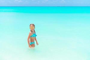 Little happy girl splashing and having fun in the shallow water. Kid in swimsuit playing with sand photo
