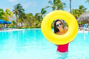 Beautiful young woman relaxing in swimming pool. Girl in outdoor pool at luxury hotel with inflatable rubber circle photo