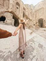 Happy young woman on background of ancient cave formations in Cappadocia following by the man. The Monastery is one of the largest religious buildings. photo