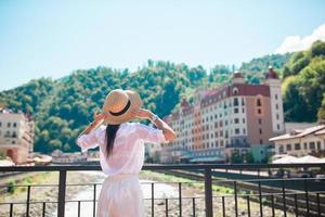 chica feliz con sombrero en el terraplén de un río de montaña en una ciudad europea. foto