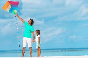 Family flying kite together at tropical white beach photo