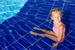 Cute happy little girl in the swimming pool looks at camera photo