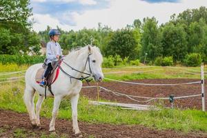 Girl riding a white horse on nature photo