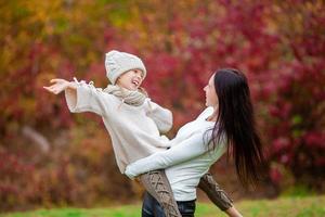 Little girl with mom outdoors in park at autumn day photo