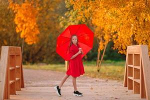 Happy child girl laughs under red umbrella photo