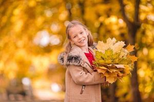 retrato de niña adorable con ramo de hojas amarillas en otoño foto