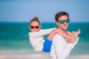 Little girl and happy dad having fun during beach vacation photo