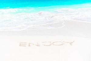 Handwritten on sandy beach with soft ocean wave on background photo