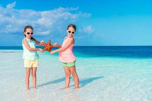 Two little happy girls have a lot of fun at tropical beach playing together photo