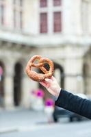 Salted pretzel in the hands of a man on background of the Vienna Opera photo