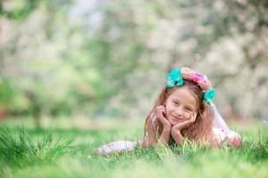 Portrait of adorable little girl in blooming cherry tree garden outdoors photo