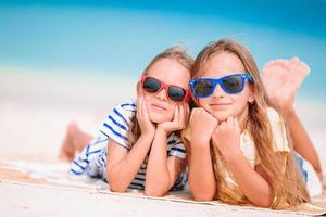 Little happy funny girls have a lot of fun at tropical beach playing together. Sunny day with rain in the sea photo