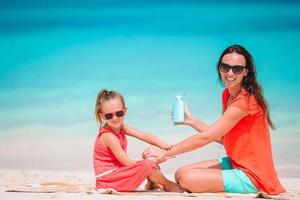 Young mother applying sun cream to daughter nose on the beach. Sun protection photo