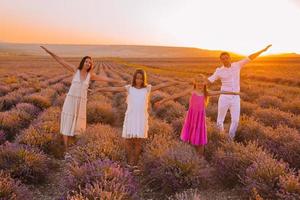 Family in lavender flowers field at sunset in white dress and hat photo