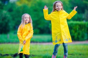 Adorable little girls wearing waterproof coat have fun outdoors photo