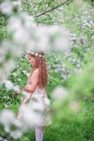 niña linda en el floreciente jardín de cerezos al aire libre foto