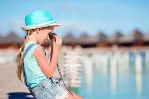 Little girl looking through binoculars in sunny day photo