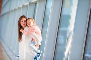 Happy family at airport sitting on suitcase with boarding pass waiting for boarding photo