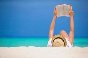 Young woman is reading on tropical white beach photo