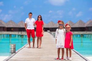 Young family of four have fun on wooden jetty during summer vacation photo