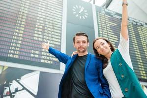 familia de dos en el fondo del aeropuerto internacional el tablero de información de vuelo foto