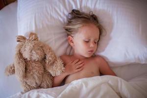 Adorable toddler taking a nap with favorite toy photo