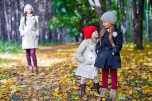 Two beautiful adorable daughter walking with his young mom in the park on a sunny autumn day photo