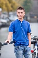 Young happy man listening to music background of canal in Amsterdam photo