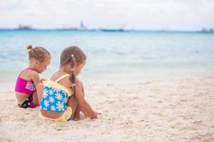 dos hermanitas en bonitos trajes de baño jugando en la playa de arena foto