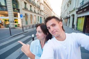 feliz pareja joven tomando selfie en parís al aire libre foto