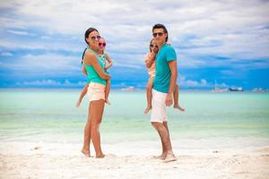 Young beautiful family with two kids looking at camera on tropical vacation photo